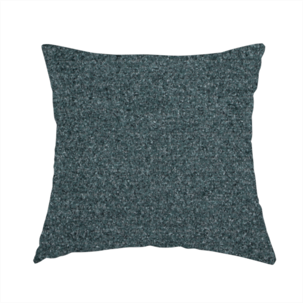 The fabric used to create this handmade cushion is a dark teal or slate blue, textured upholstery fabric.