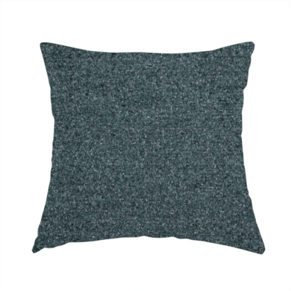 The fabric used to create this handmade cushion is a dark teal or slate blue, textured upholstery fabric.
