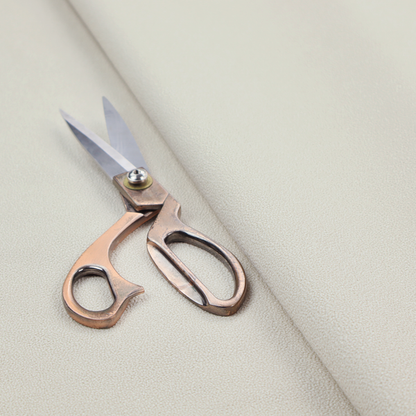 A light beige or off-white suede fabric. The textile features a highly detailed, dense, and uniform embossed pebbled pattern, giving the soft suede material an intricate, tactile texture reminiscent of shagreen.