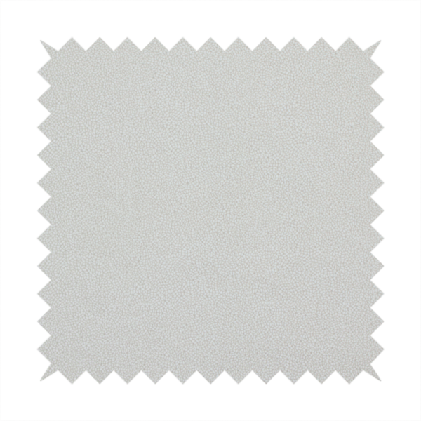 A light grey Merida Suede upholstery fabric. The textile features a highly detailed, dense, and uniform embossed pebbled pattern, giving the soft grey suede material an intricate, tactile shagreen texture.