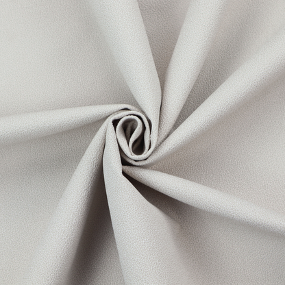 A light grey Merida Suede upholstery fabric. The textile features a highly detailed, dense, and uniform embossed pebbled pattern, giving the soft grey suede material an intricate, tactile shagreen texture.