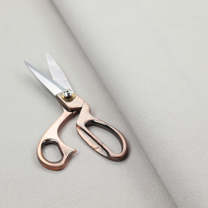 A light grey Merida Suede upholstery fabric. The textile features a highly detailed, dense, and uniform embossed pebbled pattern, giving the soft grey suede material an intricate, tactile shagreen texture.