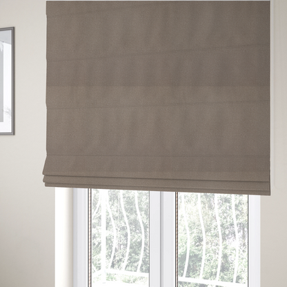 The fabric used to create these Roman blinds is a taupe or dark beige Merida Suede upholstery fabric. The textile features a highly detailed, dense, and uniform embossed pebbled pattern, giving the soft suede material an intricate, tactile shagreen texture.