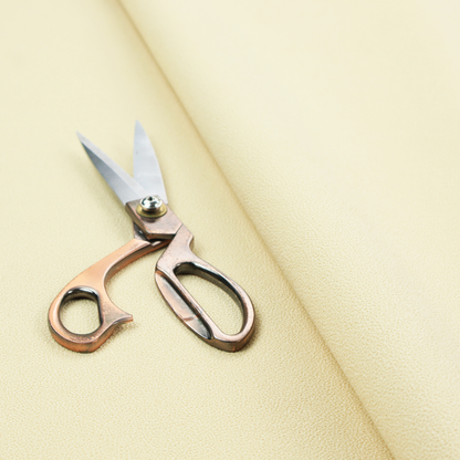 A light cream or soft ivory Merida Suede upholstery fabric. The textile features a highly detailed, dense, and uniform embossed pebbled pattern, giving the soft suede material an intricate, tactile shagreen texture.