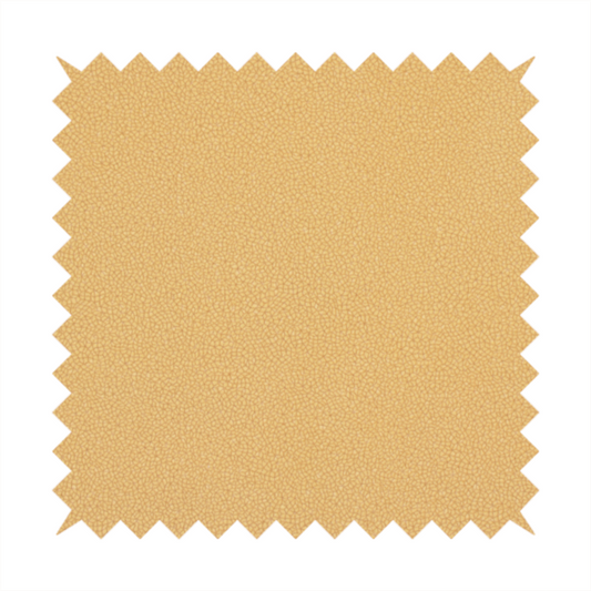 A warm ochre or golden yellow Merida Suede upholstery fabric. The textile features a highly detailed, dense, and uniform embossed pebbled pattern, giving the soft suede material an intricate, tactile shagreen texture.