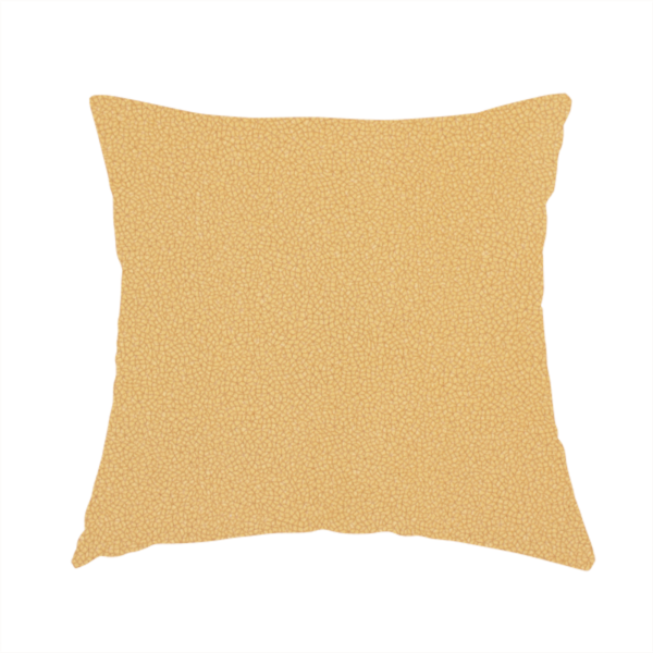 The fabric used to create this handmade cushion is a warm ochre or golden yellow Merida Suede upholstery fabric. The textile features a highly detailed, dense, and uniform embossed pebbled pattern, giving the soft suede material an intricate, tactile shagreen texture.