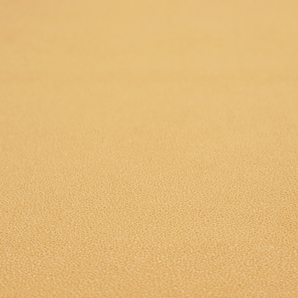A warm ochre or golden yellow Merida Suede upholstery fabric. The textile features a highly detailed, dense, and uniform embossed pebbled pattern, giving the soft suede material an intricate, tactile shagreen texture.
