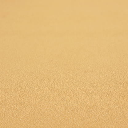 A warm ochre or golden yellow Merida Suede upholstery fabric. The textile features a highly detailed, dense, and uniform embossed pebbled pattern, giving the soft suede material an intricate, tactile shagreen texture.
