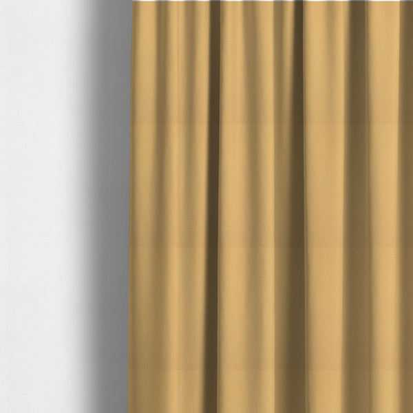 The fabric used to create these made-to-measure curtains is a warm ochre or golden yellow Merida Suede upholstery fabric. The textile features a highly detailed, dense, and uniform embossed pebbled pattern, giving the soft suede material an intricate, tactile shagreen texture.