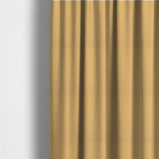 The fabric used to create these made-to-measure curtains is a warm ochre or golden yellow Merida Suede upholstery fabric. The textile features a highly detailed, dense, and uniform embossed pebbled pattern, giving the soft suede material an intricate, tactile shagreen texture.