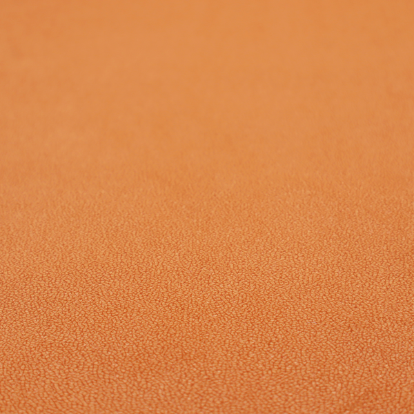 A bright orange or tangerine Merida Suede upholstery fabric. The textile features a highly detailed, dense, and uniform embossed pebbled pattern, giving the soft suede material an intricate, tactile shagreen texture.