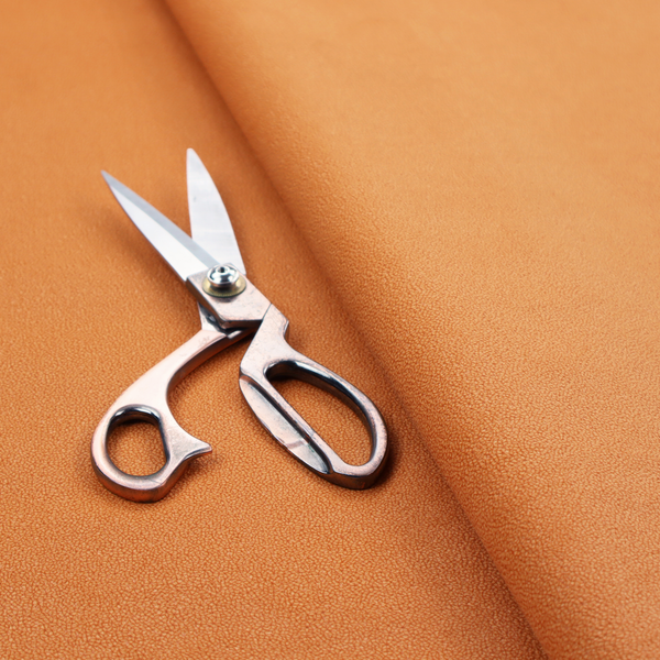A bright orange or tangerine Merida Suede upholstery fabric. The textile features a highly detailed, dense, and uniform embossed pebbled pattern, giving the soft suede material an intricate, tactile shagreen texture.