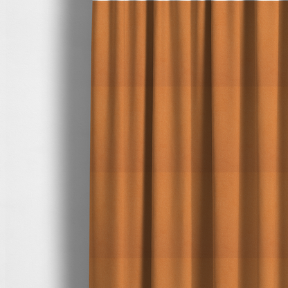 The fabric used to create these made-to-measure curtains is a bright orange or tangerine Merida Suede upholstery fabric. The textile features a highly detailed, dense, and uniform embossed pebbled pattern, giving the soft suede material an intricate, tactile shagreen texture.