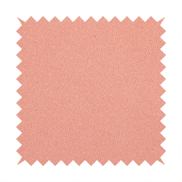 A soft salmon pink or coral Merida Suede upholstery fabric. The textile features a highly detailed, dense, and uniform embossed pebbled pattern, giving the soft suede material an intricate, tactile shagreen texture.