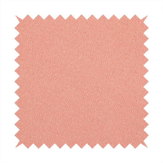 A soft salmon pink or coral Merida Suede upholstery fabric. The textile features a highly detailed, dense, and uniform embossed pebbled pattern, giving the soft suede material an intricate, tactile shagreen texture.