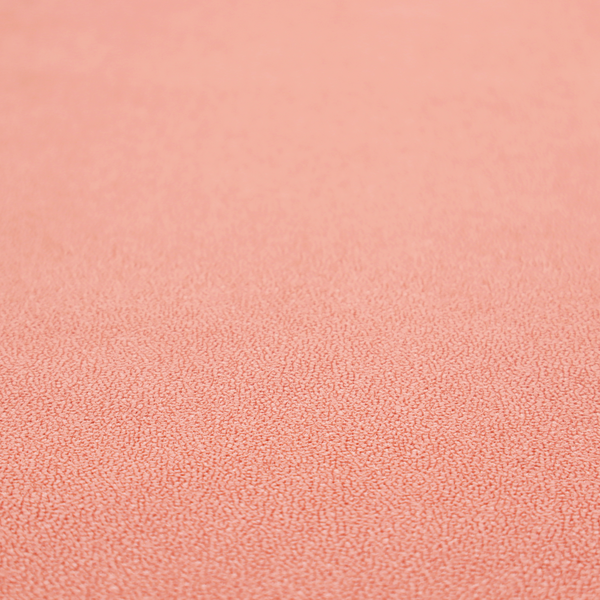A soft salmon pink or coral Merida Suede upholstery fabric. The textile features a highly detailed, dense, and uniform embossed pebbled pattern, giving the soft suede material an intricate, tactile shagreen texture.