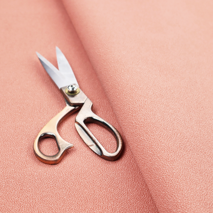 A soft salmon pink or coral Merida Suede upholstery fabric. The textile features a highly detailed, dense, and uniform embossed pebbled pattern, giving the soft suede material an intricate, tactile shagreen texture.