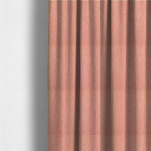 The fabric used to create these made-to-measure curtains is a soft salmon pink or coral Merida Suede upholstery fabric. The textile features a highly detailed, dense, and uniform embossed pebbled pattern, giving the soft suede material an intricate, tactile shagreen texture.