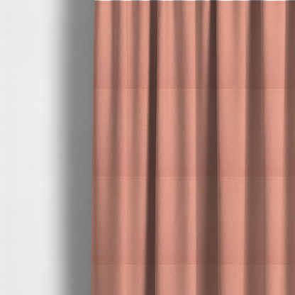The fabric used to create these made-to-measure curtains is a soft salmon pink or coral Merida Suede upholstery fabric. The textile features a highly detailed, dense, and uniform embossed pebbled pattern, giving the soft suede material an intricate, tactile shagreen texture.