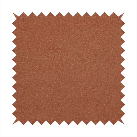 A warm terracotta or rust orange Merida Suede upholstery fabric. The textile features a highly detailed, dense, and uniform embossed pebbled pattern, giving the soft suede material an intricate, tactile shagreen texture.