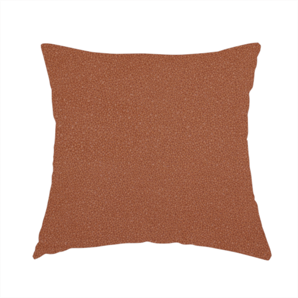 The fabric used to create this handmade cushion is a warm terracotta or rust orange Merida Suede upholstery fabric. The textile features a highly detailed, dense, and uniform embossed pebbled pattern, giving the soft suede material an intricate, tactile shagreen texture.