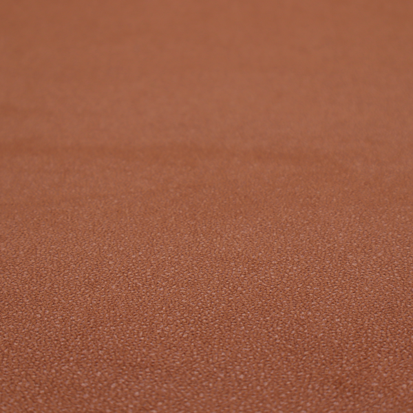 A warm terracotta or rust orange Merida Suede upholstery fabric. The textile features a highly detailed, dense, and uniform embossed pebbled pattern, giving the soft suede material an intricate, tactile shagreen texture.