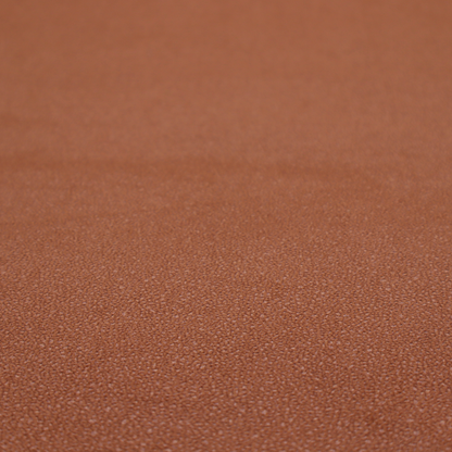A warm terracotta or rust orange Merida Suede upholstery fabric. The textile features a highly detailed, dense, and uniform embossed pebbled pattern, giving the soft suede material an intricate, tactile shagreen texture.