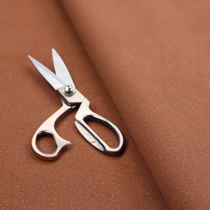 A warm terracotta or rust orange Merida Suede upholstery fabric. The textile features a highly detailed, dense, and uniform embossed pebbled pattern, giving the soft suede material an intricate, tactile shagreen texture.