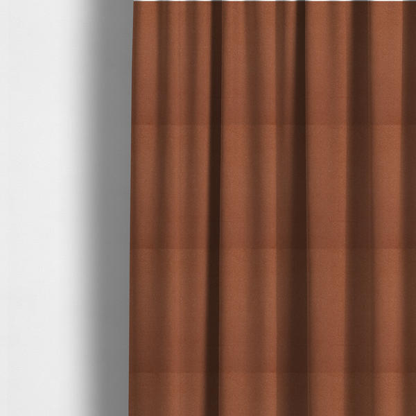 The fabric used to create these made-to-measure curtains is a warm terracotta or rust orange Merida Suede upholstery fabric. The textile features a highly detailed, dense, and uniform embossed pebbled pattern, giving the soft suede material an intricate, tactile shagreen texture.
