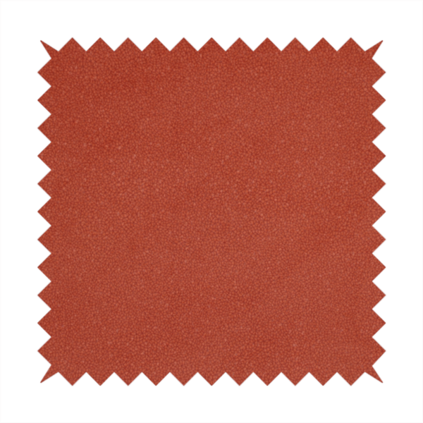 A vibrant brick red or rust Merida Suede upholstery fabric. The textile features a highly detailed, dense, and uniform embossed pebbled pattern, giving the soft suede material an intricate, tactile shagreen texture.