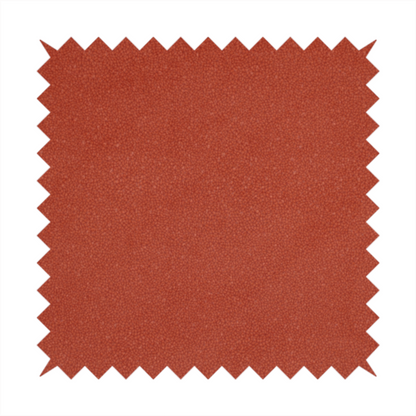 A vibrant brick red or rust Merida Suede upholstery fabric. The textile features a highly detailed, dense, and uniform embossed pebbled pattern, giving the soft suede material an intricate, tactile shagreen texture.