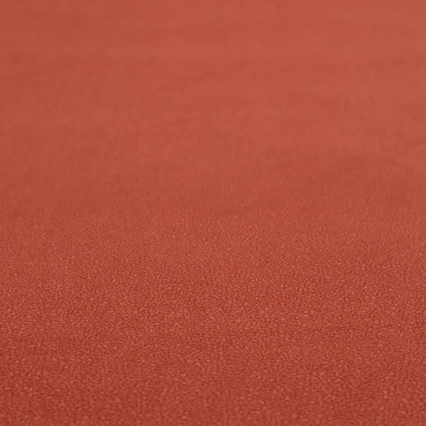 A vibrant brick red or rust Merida Suede upholstery fabric. The textile features a highly detailed, dense, and uniform embossed pebbled pattern, giving the soft suede material an intricate, tactile shagreen texture.