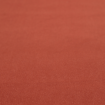 A vibrant brick red or rust Merida Suede upholstery fabric. The textile features a highly detailed, dense, and uniform embossed pebbled pattern, giving the soft suede material an intricate, tactile shagreen texture.