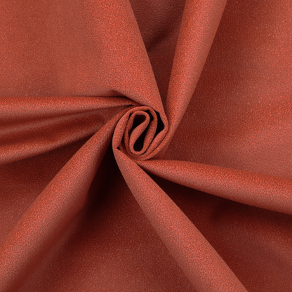 A vibrant brick red or rust Merida Suede upholstery fabric. The textile features a highly detailed, dense, and uniform embossed pebbled pattern, giving the soft suede material an intricate, tactile shagreen texture.