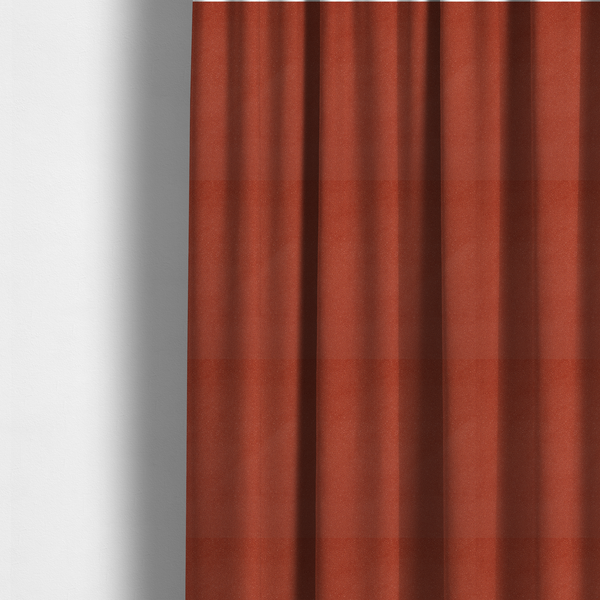 The fabric used to create these made-to-measure curtains is a vibrant brick red or rust Merida Suede upholstery fabric. The textile features a highly detailed, dense, and uniform embossed pebbled pattern, giving the soft suede material an intricate, tactile shagreen texture.