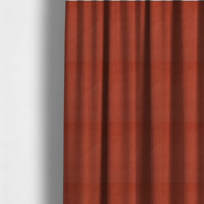 The fabric used to create these made-to-measure curtains is a vibrant brick red or rust Merida Suede upholstery fabric. The textile features a highly detailed, dense, and uniform embossed pebbled pattern, giving the soft suede material an intricate, tactile shagreen texture.