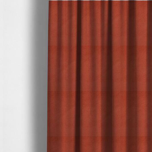 The fabric used to create these made-to-measure curtains is a vibrant brick red or rust Merida Suede upholstery fabric. The textile features a highly detailed, dense, and uniform embossed pebbled pattern, giving the soft suede material an intricate, tactile shagreen texture.