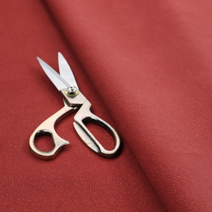 A rich crimson or deep red Merida Suede upholstery fabric. The textile features a highly detailed, dense, and uniform embossed pebbled pattern, giving the soft suede material an intricate, tactile shagreen texture.