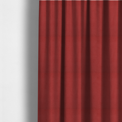 The fabric used to create these made-to-measure curtains is a rich crimson or deep red Merida Suede upholstery fabric. The textile features a highly detailed, dense, and uniform embossed pebbled pattern, giving the soft suede material an intricate, tactile shagreen texture.