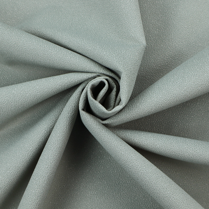 A Merida Suede upholstery fabric in a light sage or pale eucalyptus green colour.