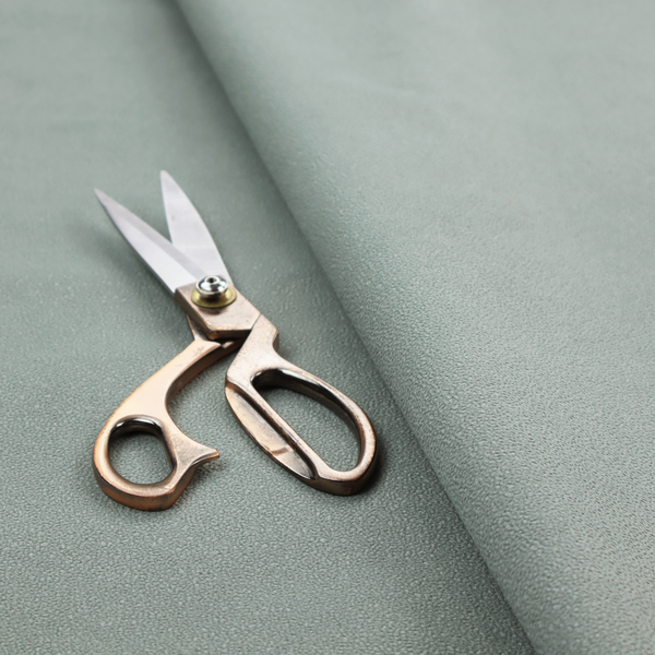 A Merida Suede upholstery fabric in a light sage or pale eucalyptus green colour.
