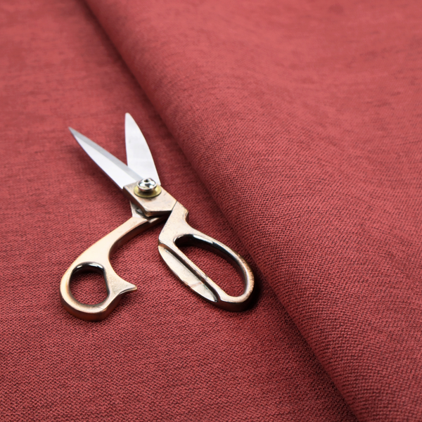 A finely textured weave in a dusty rose or muted red colour. The material features a subtle heathered look with tiny variations of darker and lighter threads throughout.