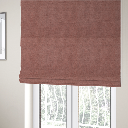 The fabric used to create these Roman blinds is a finely textured weave in a soft, dusty rose or blush pink shade. The material has a subtle heathered appearance with fine variations of lighter pink and darker undertones throughout.