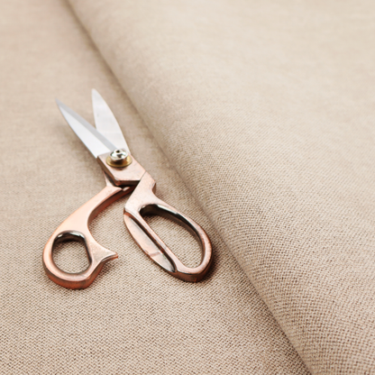 A finely textured weave in a warm beige or natural linen shade. The material features a subtle heathered look with tiny flecks of light tan and neutral undertones throughout.