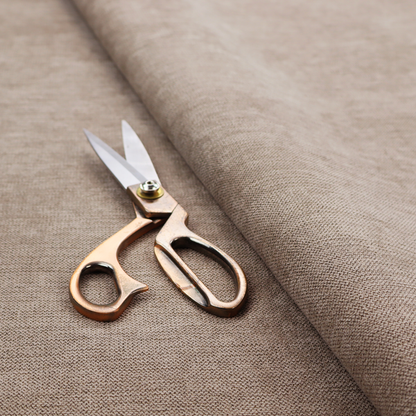 A finely textured weave in a warm taupe or light brownish-grey shade. The material features a subtle heathered look with finely blended threads of tan, cream, and soft brown undertones throughout.