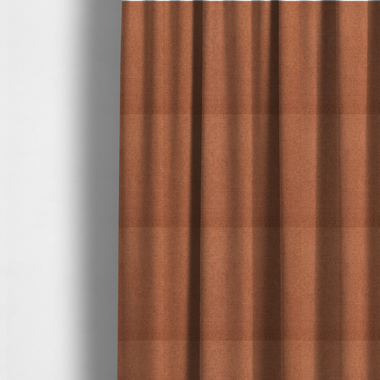 The fabric used to create these made-to-measure curtains is a finely textured weave in a bright ginger, amber, or light rust shade. The material features a subtle heathered look with finely blended threads of warm orange and darker neutral undertones throughout.
