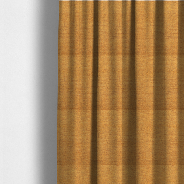 The fabric used to create these made-to-measure curtains is a finely textured weave in a rich mustard yellow or golden-amber shade. The material features a subtle heathered look with finely blended threads of warm yellow and darker neutral undertones throughout.