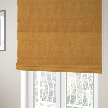 the fabric used to create these Roman blinds is a finely textured weave in a rich mustard yellow or golden-amber shade. The material features a subtle heathered look with finely blended threads of warm yellow and darker neutral undertones throughout.