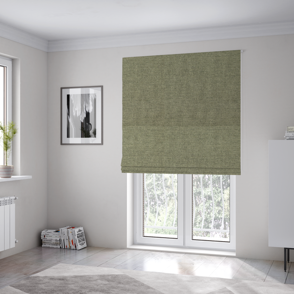 The fabric used to create these Roman blinds is a finely textured weave in a muted sage, olive, or light moss green shade. The material features a subtle heathered look with finely blended threads of earthy green and darker neutral undertones throughout.