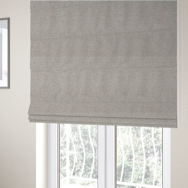 The fabric used to create these Roman blinds is a finely textured weave in a pale silver, heather grey, or light ash tone. The material features a subtle heathered look with finely blended threads of cool grey and white undertones throughout.